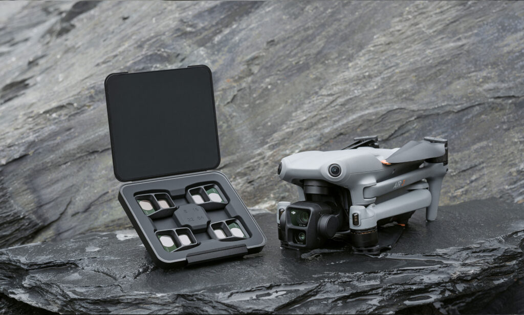 DJI Air 3 drone with a set of drone filters in an open case, resting on a rocky surface, highlighting the importance of drone filters for aerial photography and videography.